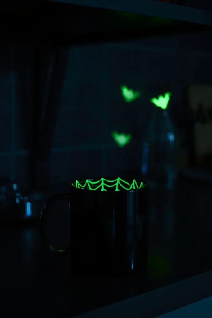  nighttime kitchen shot, featuring a black mug with a faintly glowing green spiderweb pattern 