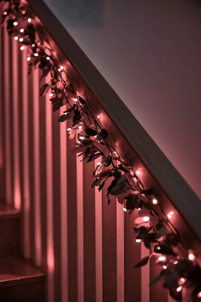 staircase railing, featuring faux eucalyptus garland woven with pink-toned fairy lights 