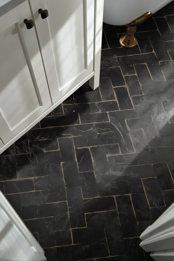 19 Black Bathroom Ideas That Are Dramatic, Chic & Completely Stunning 12 bathroom floor detail, featuring black herringbone-pattern porcelain tile