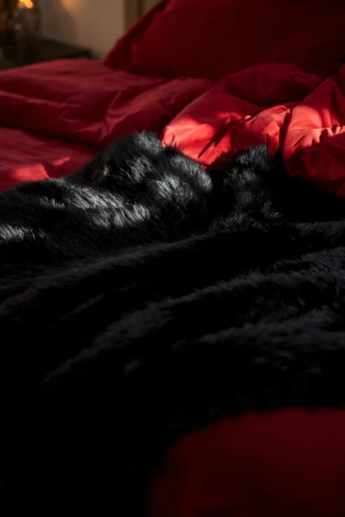 21 Vampy Romantic Bedroom Ideas for a Moody, Gothic-Chic Retreat 14 bed styling detail shot, featuring a black faux fur throw drape