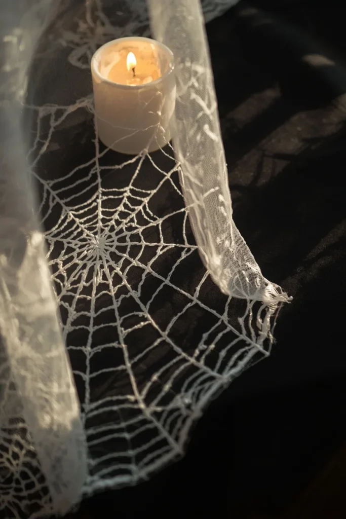 macro-style table detail shot, featuring sheer lace spiderweb overlay draped loosely